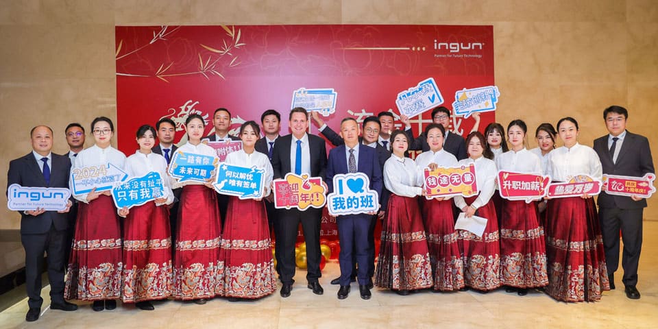 Festive group photo of INGUN employees from China in festive attire and holding paper signs with congratulations in their hands